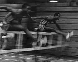 Photo of George Byers in hurdle race at Allen Fieldhouse, Feb 1967